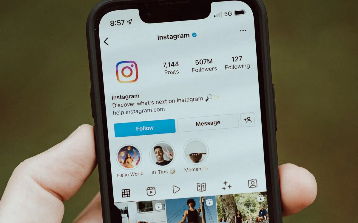 Hand holding a phone showing an Instagram profile