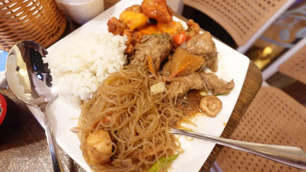 A plate of glass noodles, rice and chicken with a spoon and fork